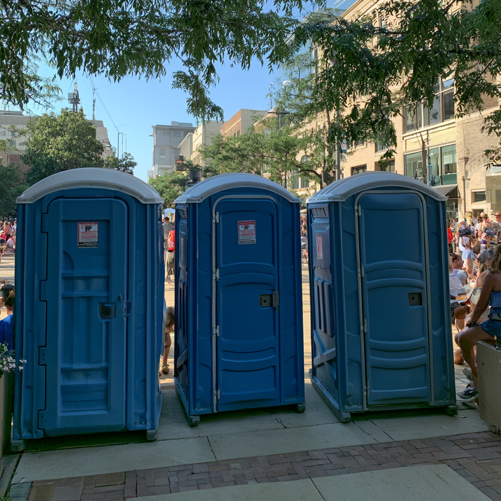 Three porta potties at an outdoor event downtown